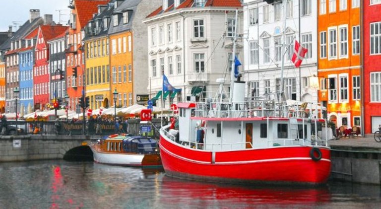 Row of colorful houses and a red and white wooden boat in Nyhavn.