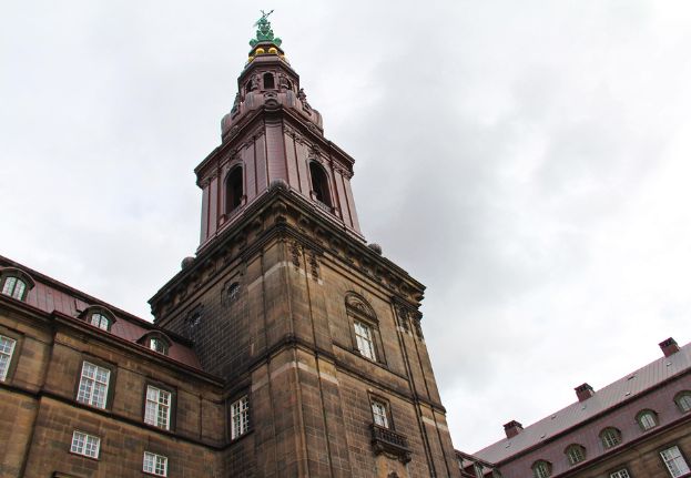 The tower at Christiansborg Palace in Copenhagen, seen from below against a cloudy sky