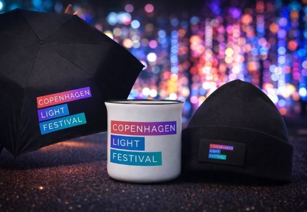 Copenhagen Light Festival souvenirs: umbrella, mug, and knitted hat with colorful lights in background