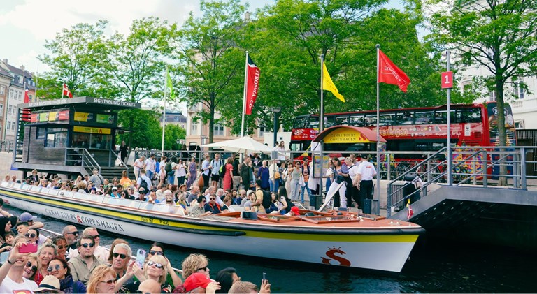 Two canal boats and a red doubledecker sightseeing bus and many guests.